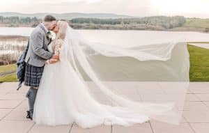 The bride's veil trails in the wind in the grounds of the Lochside